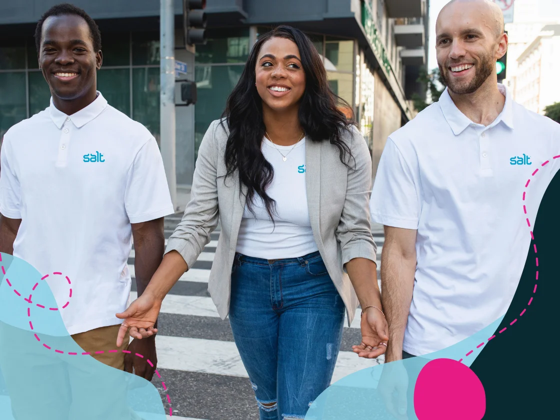 Three team members in Salt branded clothing walk across a city street, smiling