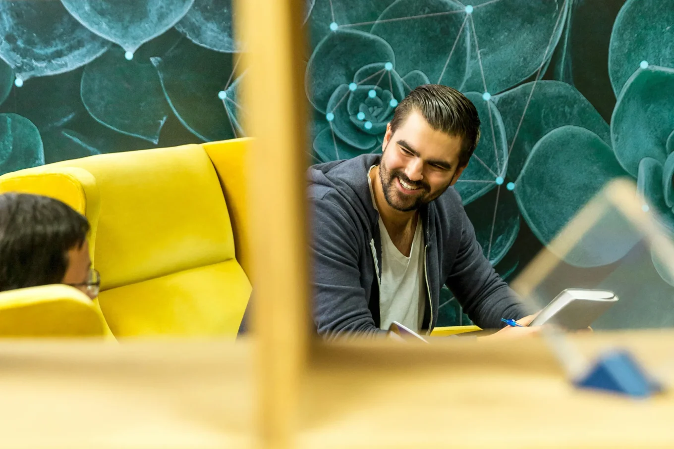 Coworkers sitting on a yellow couch smiling