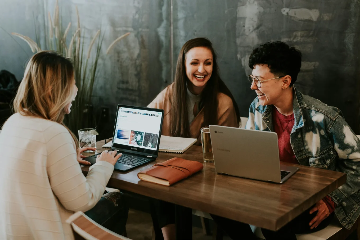 Three coworkers sitting at a desk together laughing
