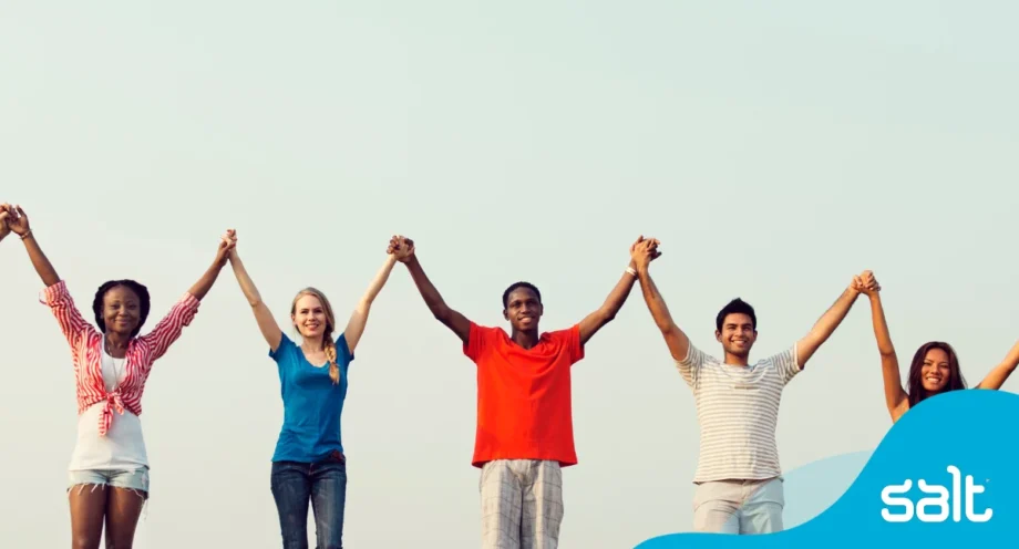 Diverse group of people standing side by side holding hands up in the air, representing allyship