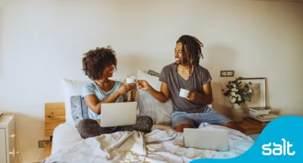 Two people at home on their beds busy with a morning routine of coffee and starting work from home