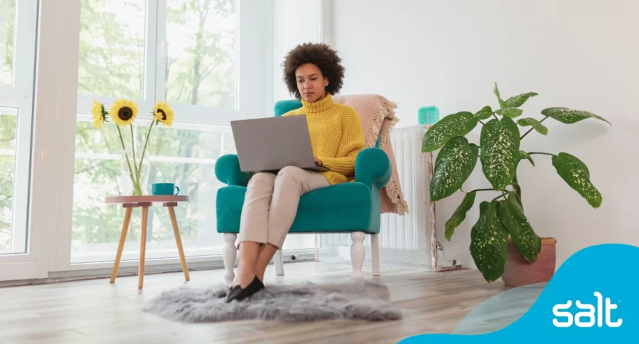 A woman sitting in a blue chair working on a laptop