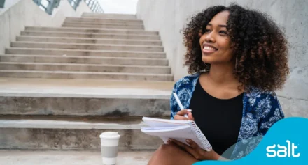 A woman sitting on stairs writing in her notebook