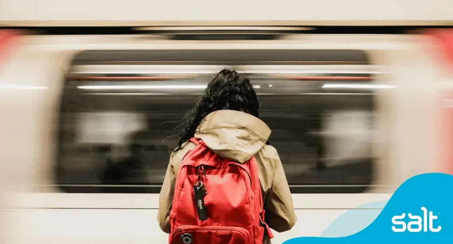 A person with a backpack on the underground tube with a train passing