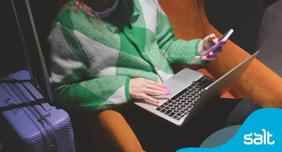A freelancer working on laptop and phone with travel bag nearby