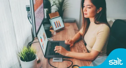 Woman sitting at a desk analysing data on digital devices
