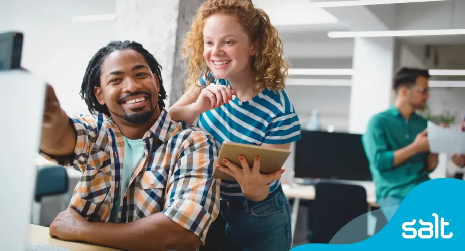 Man and woman smiling while reading something on a computer