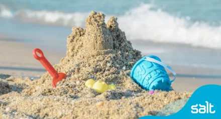 Sandcastle and toys on the beach with waves approaching