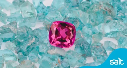 Close up of a pink gemstone in a pile of blue glass pieces