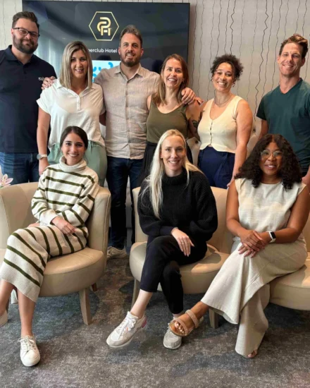 A group of ten team members pose together indoors, smiling during a leadership strategy day, with some seated and others standing behind them
