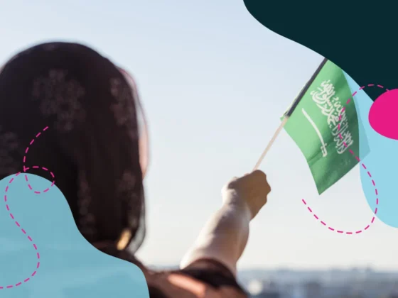 Close up of Saudi woman in traditional clothing waving the Saudi flag